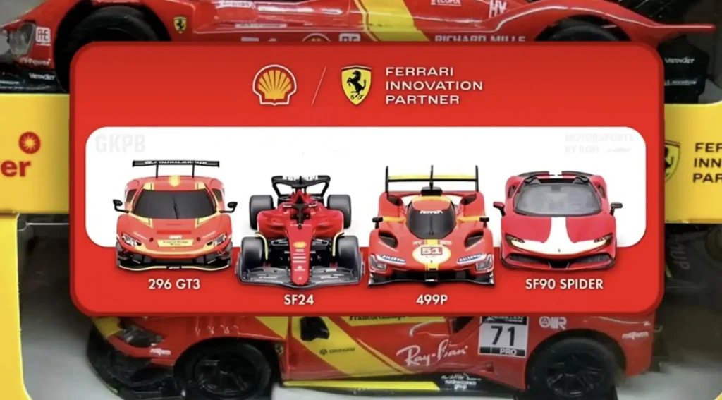 Uma imagem mostra uma coleção de quatro carros colecionáveis da Ferrari, dispostos horizontalmente dentro de uma caixa vermelha. Acima dos carros, em um fundo vermelho, estão os logotipos da Shell e da Ferrari, acompanhados do texto "FERRARI INNOVATION PARTNER". Os carros são identificados pelos seus modelos: "296 GT3", "SF24", "499P" e "SF90 SPIDER". As miniaturas são vermelhas com detalhes em branco e outras cores, simulando os carros de corrida reais. A caixa é translúcida e revela outros carros colecionáveis na parte inferior.