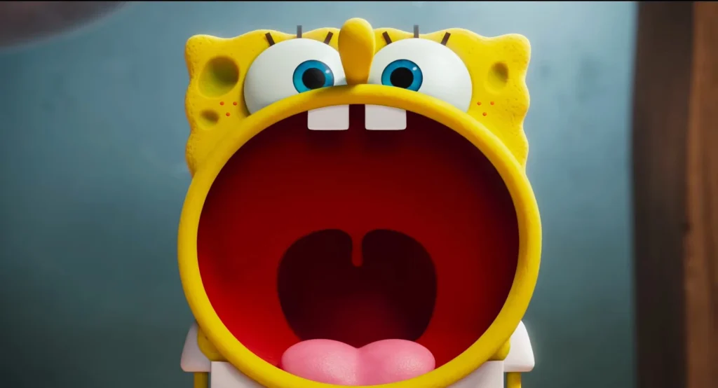 Close-up de Bob Esponja gritando com a boca bem aberta, mostrando seus dentes e língua, em um fundo desfocado.