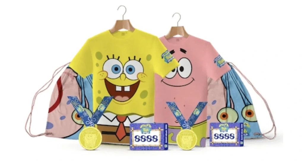 Uma imagem promocional vibrante mostrando um kit de corrida inspirado no Bob Esponja. À esquerda, uma camiseta amarela exibe o rosto sorridente do Bob Esponja. À direita, uma camiseta rosa apresenta o rosto do Patrick Estrela. Ambas as camisetas estão penduradas em cabides e, atrás de cada uma, há uma sacola de cordão com os mesmos personagens. Na frente, há duas medalhas de ouro com fitas azuis decoradas, cada uma ao lado de um bib de corrida roxo com o número "8888" e o logotipo "Bob Esponja".