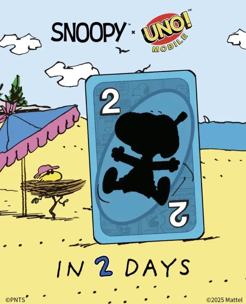 A imagem mostra um cenário de praia ensolarado com o Snoopy e o Woodstock. No centro, há uma carta "UNO Mobile" azul com o símbolo de um "2" em ambos os lados e uma silhueta de Charlie Brown no meio. A carta é grande e parece flutuar na areia.