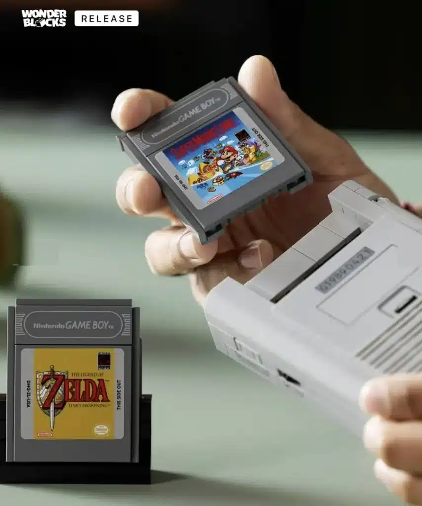 Uma pessoa segura um console Game Boy branco na mão direita e um cartucho de jogo "Super Mario Land" na mão esquerda, prestes a inseri-lo. Outro cartucho de jogo, "The Legend of Zelda: Link's Awakening", está em um suporte preto no canto inferior esquerdo da imagem. No canto superior esquerdo, há o logo "WONDER BLOCKS" e a palavra "RELEASE".