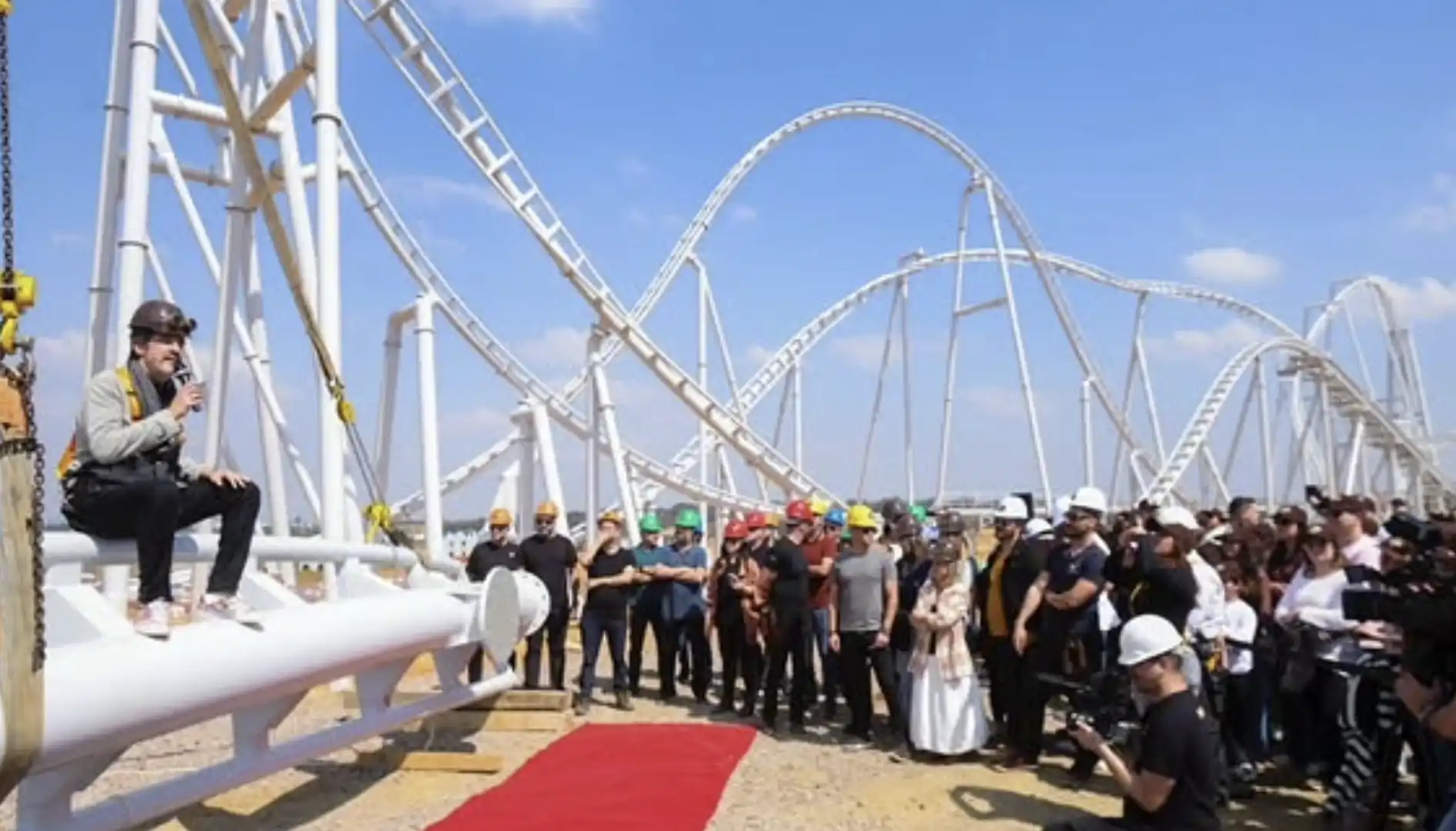 Imagem de Alexandre Costa, dono da Cacau Show, discursando em um pódio improvisado em uma das estruturas da montanha-russa do Cacau Park para uma plateia de convidados e jornalistas.