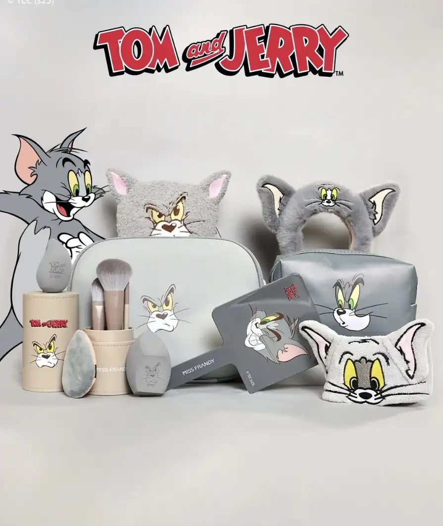 Uma coleção de maquiagem e acessórios com o tema de Tom e Jerry, apresentando produtos de beleza cinza e bege decorados com os rostos dos personagens.