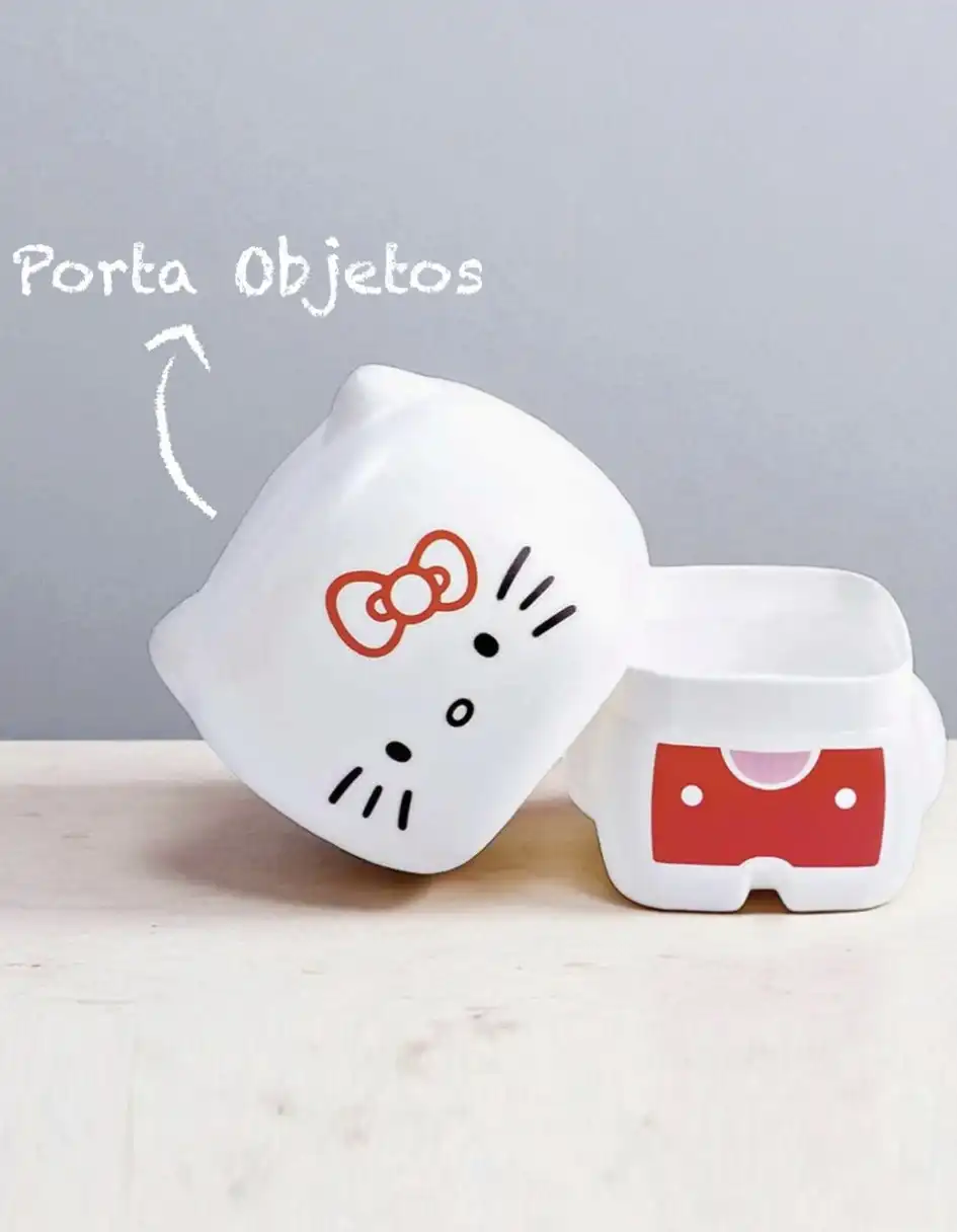 Um porta-objetos da Hello Kitty, branco e com detalhes em vermelho e preto, composto por duas partes separadas. A parte de cima, com o rosto da Hello Kitty, está inclinada sobre a base, que possui um detalhe em formato de lacinho vermelho.