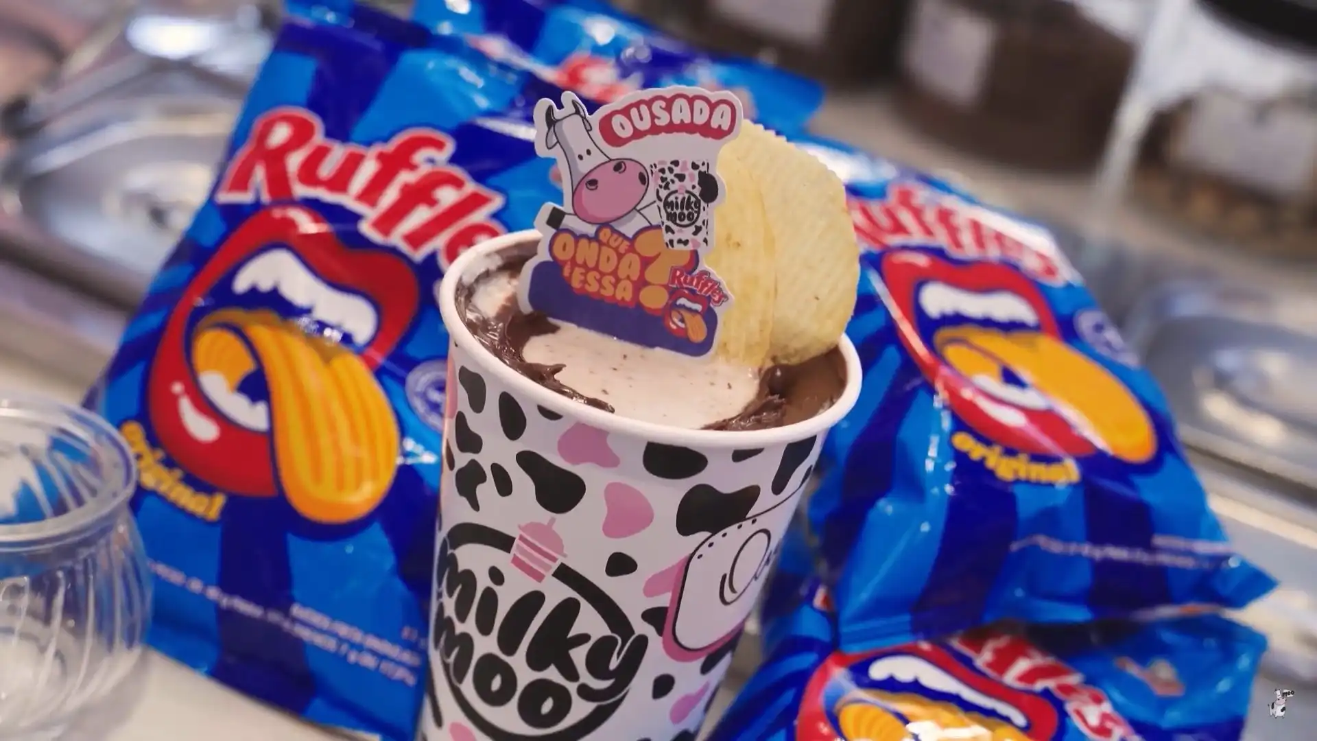 Copo de Milky Moo com cobertura de chocolate e batata Ruffles, rodeado por embalagens de Ruffles.