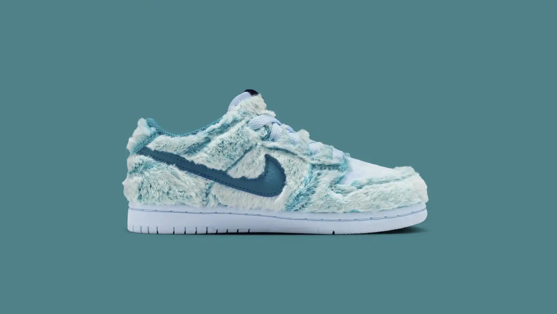 Vista lateral de um tênis Nike Dunk Low "Abominável Homem das Neves" com pelagem azul e branca e o logo Swoosh azul escuro.