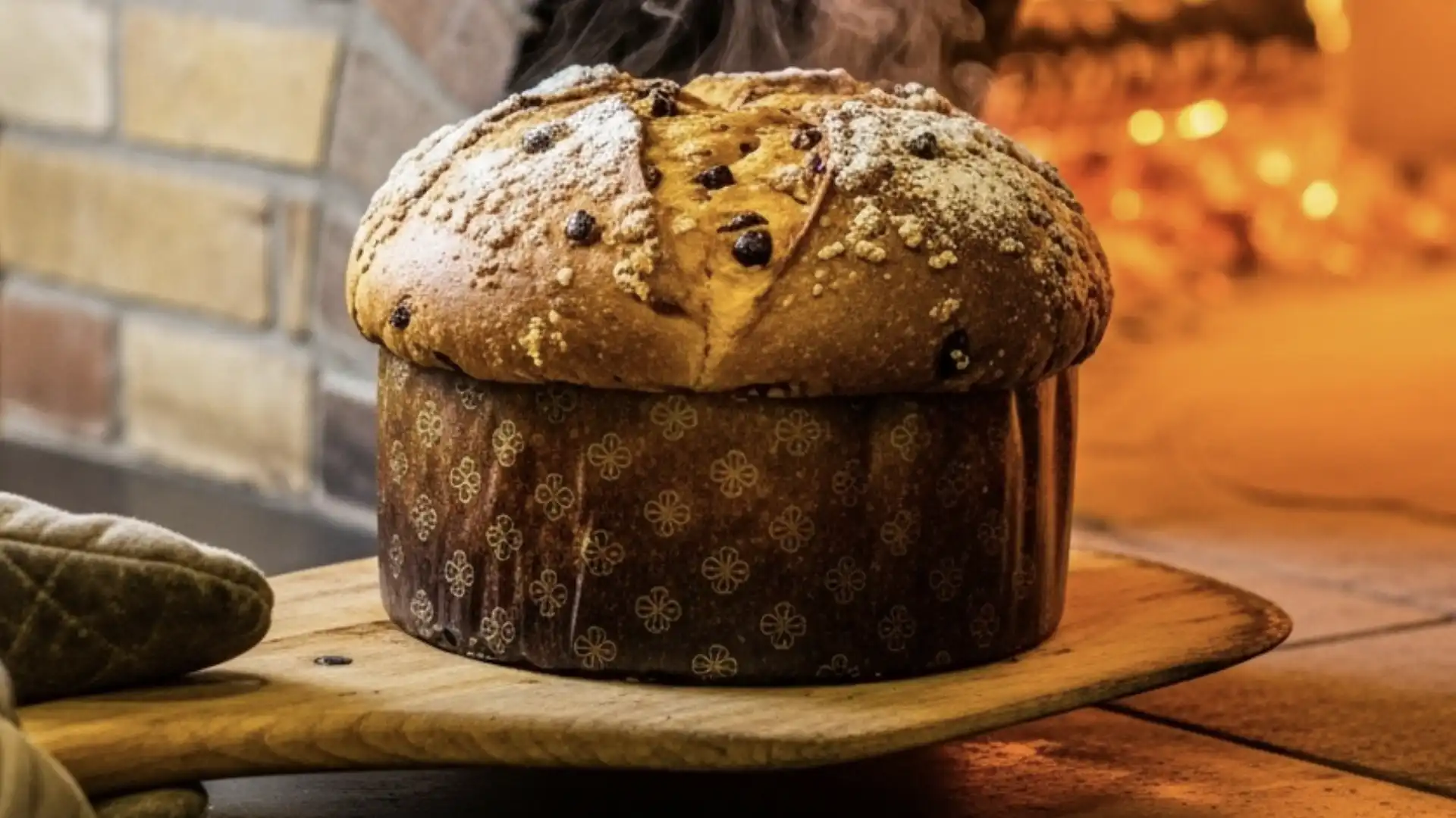 panetone recém-assado, ainda soltando vapor, sendo retirado de um forno de tijolos.