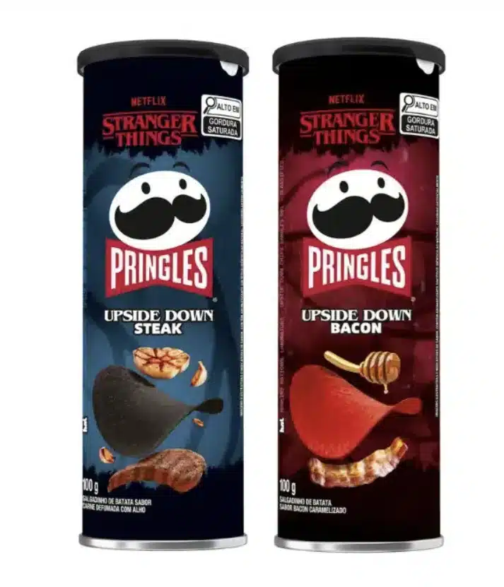 Dois tubos de Pringles de edição especial de Stranger Things. Um tubo azul escuro, à esquerda, é de sabor "Upside Down Steak". Um tubo vermelho escuro, à direita, é de sabor "Upside Down Bacon".