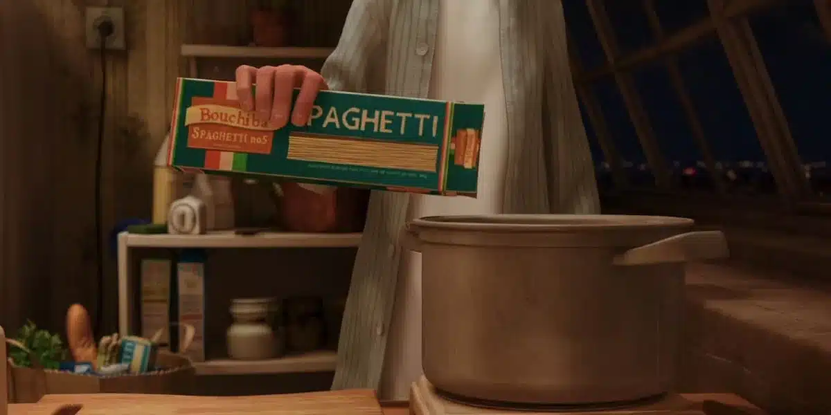 Uma pessoa está segurando uma caixa de espaguete "Bouchiba Spaghetti no 5" sobre uma panela em uma cozinha.
