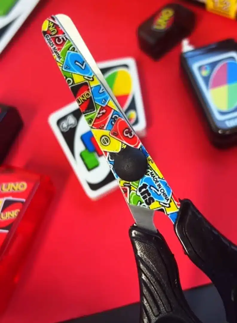 Tesoura com tema UNO da marca TRIS em close-up.
