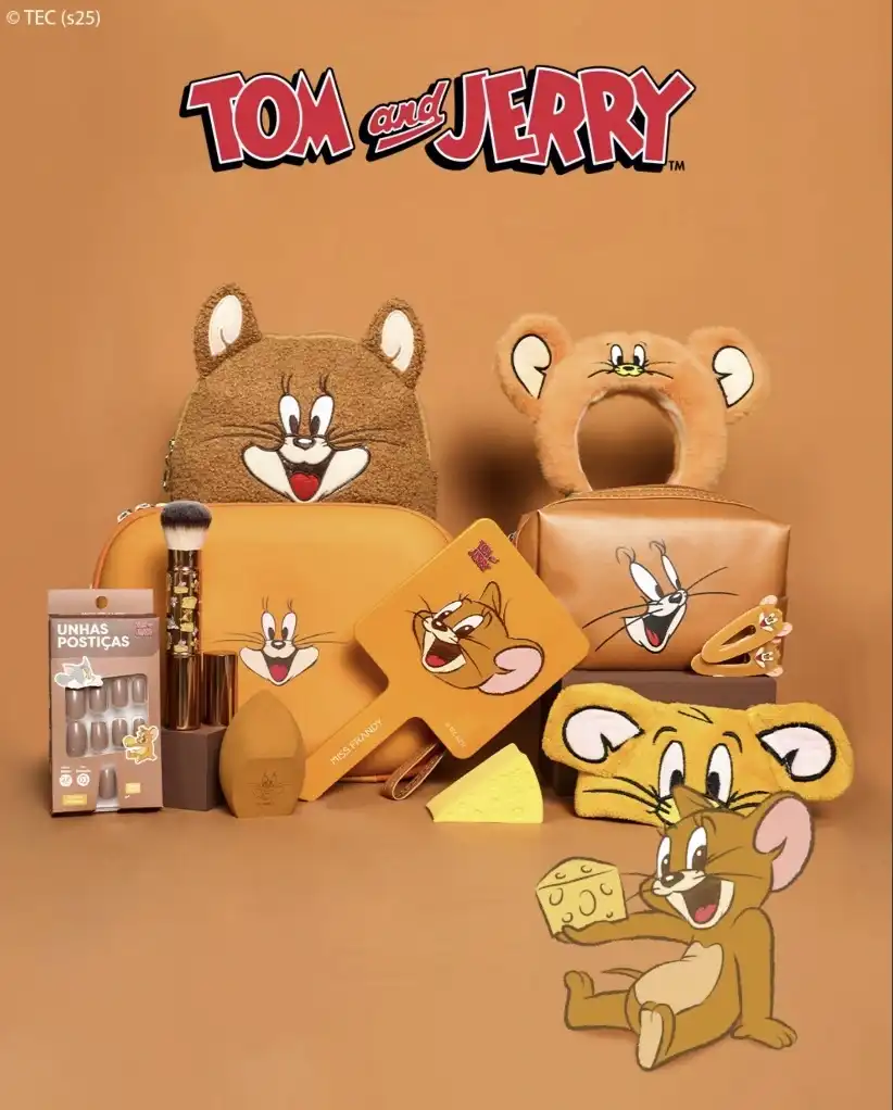 Uma coleção de produtos de maquiagem e acessórios inspirados em Tom e Jerry, predominantemente nas cores marrom e laranja. Há uma mochila em formato de Jerry, uma tiara com orelhas de Jerry, um espelho de mão com a imagem de Jerry sorrindo, e diversas necessaires e bolsas de maquiagem com estampas de Jerry. Também há um conjunto de pincéis de maquiagem, uma esponja de maquiagem e um pacote de unhas postiças neutras.
