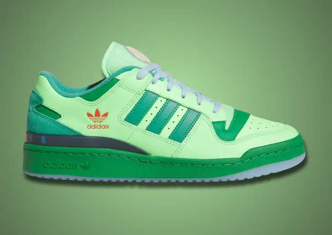 Tênis Adidas Forum Low, da colaboração "The Simpsons Treehouse of Horror", em tons de verde e com detalhes na cor verde escura. O logotipo da Adidas e a palavra "Adidas" estão em laranja. O solado é em um tom de verde vibrante e o cadarço é verde claro.