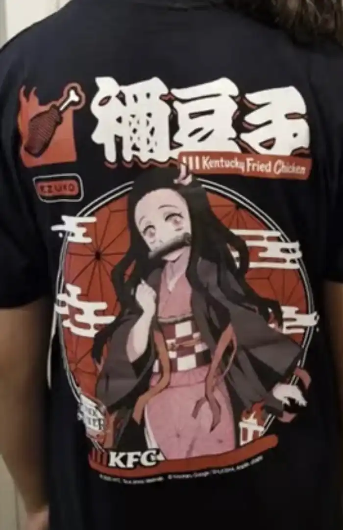 Camiseta preta com estampa da personagem Nezuko Kamado do anime Demon Slayer em um círculo, com os logos do KFC e de uma perna de frango ao lado.