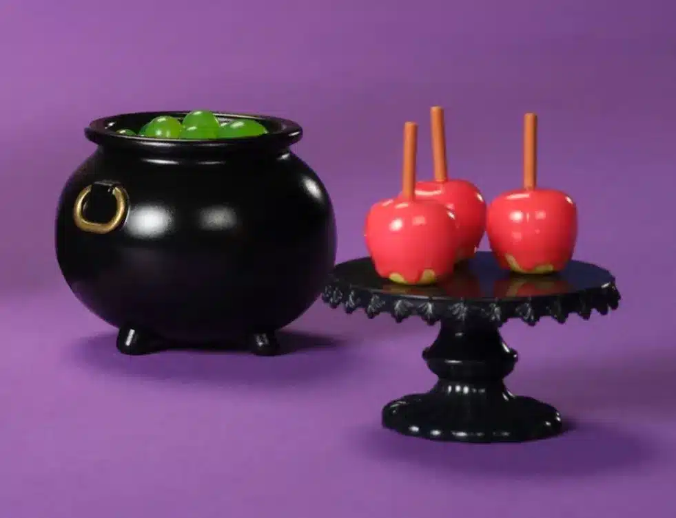 Miniaturas de itens de Halloween: um caldeirão preto e maçãs do amor vermelhas.