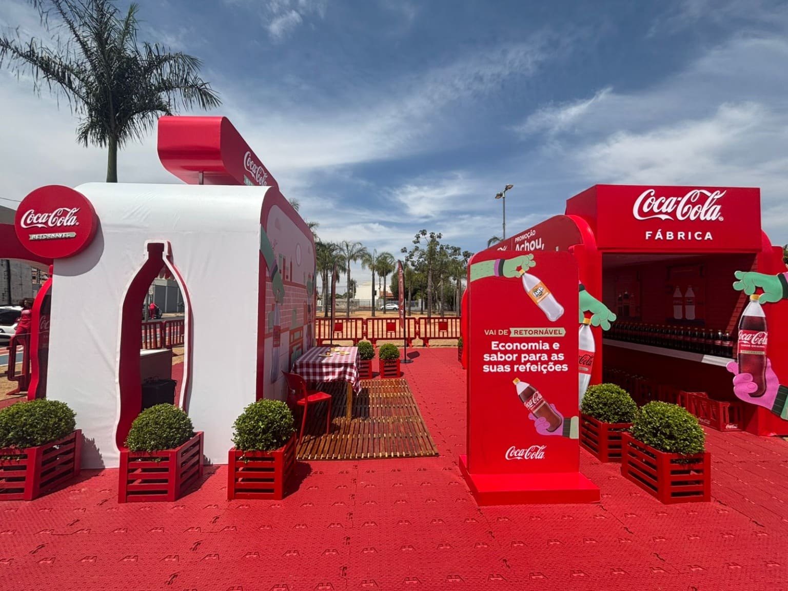 Estande de ativação da Coca-Cola Femsa ao ar livre com cores vermelhas e brancas, promovendo a garrafa retornável.