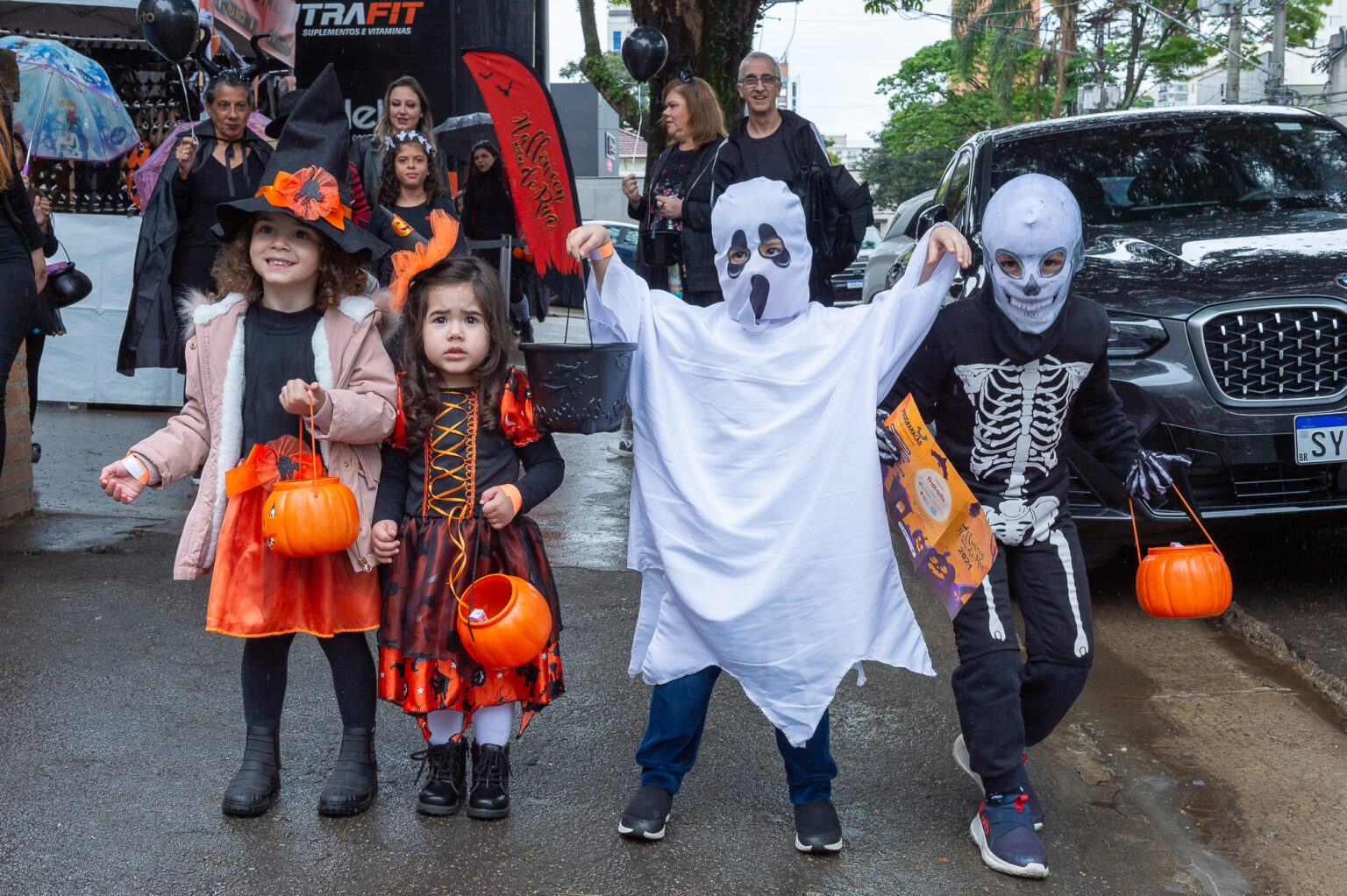 Crianças fantasiadas de Halloween, incluindo bruxa, fantasma e esqueleto, participando de um evento da Panco.