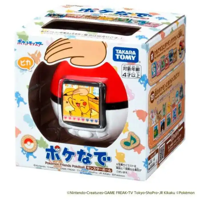 Uma imagem mostra a caixa de um brinquedo Takara Tomy chamado "Pokenade". A caixa branca tem ilustrações de vários Pokémon, incluindo Pikachu. Uma grande janela na frente exibe o brinquedo principal: uma Poké Bola com uma pequena tela que mostra um desenho de Pikachu acenando. O design da caixa é alegre e colorido.