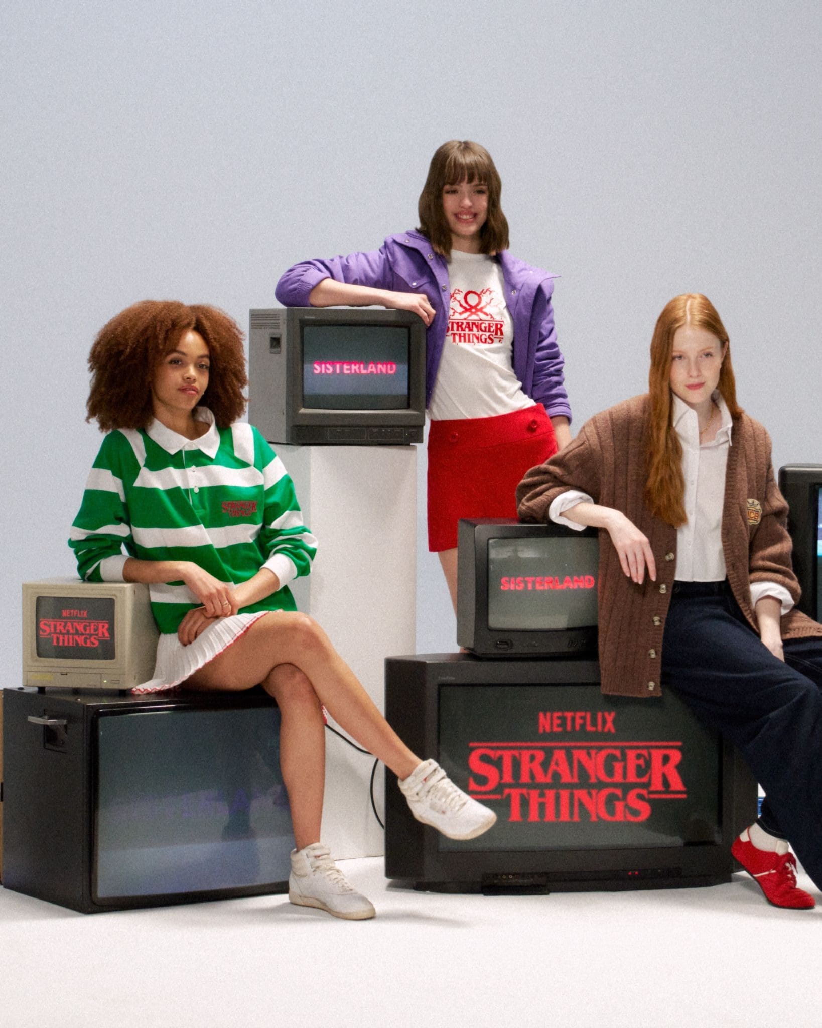 Três modelos vestindo roupas inspiradas nos anos 80, posando em torno de televisões retrô que exibem logotipos de "Stranger Things" e "Sisterland", como parte de uma campanha da Benetton.