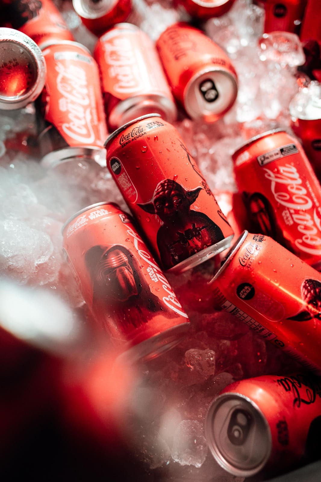 Latas de Coca-Cola Zero Açúcar da edição especial Star Wars, incluindo a lata com Yoda, em meio a cubos de gelo.