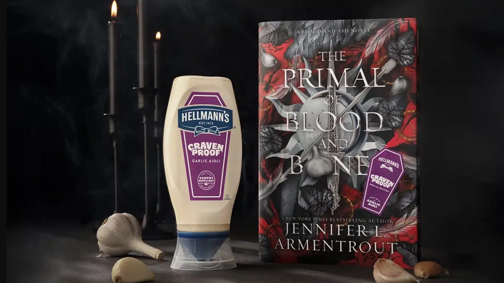Uma garrafa de maionese Hellmann's de alho "Craven Proof" ao lado de um livro "The Primal of Blood and Bone" e dentes de alho, com velas acesas ao fundo.