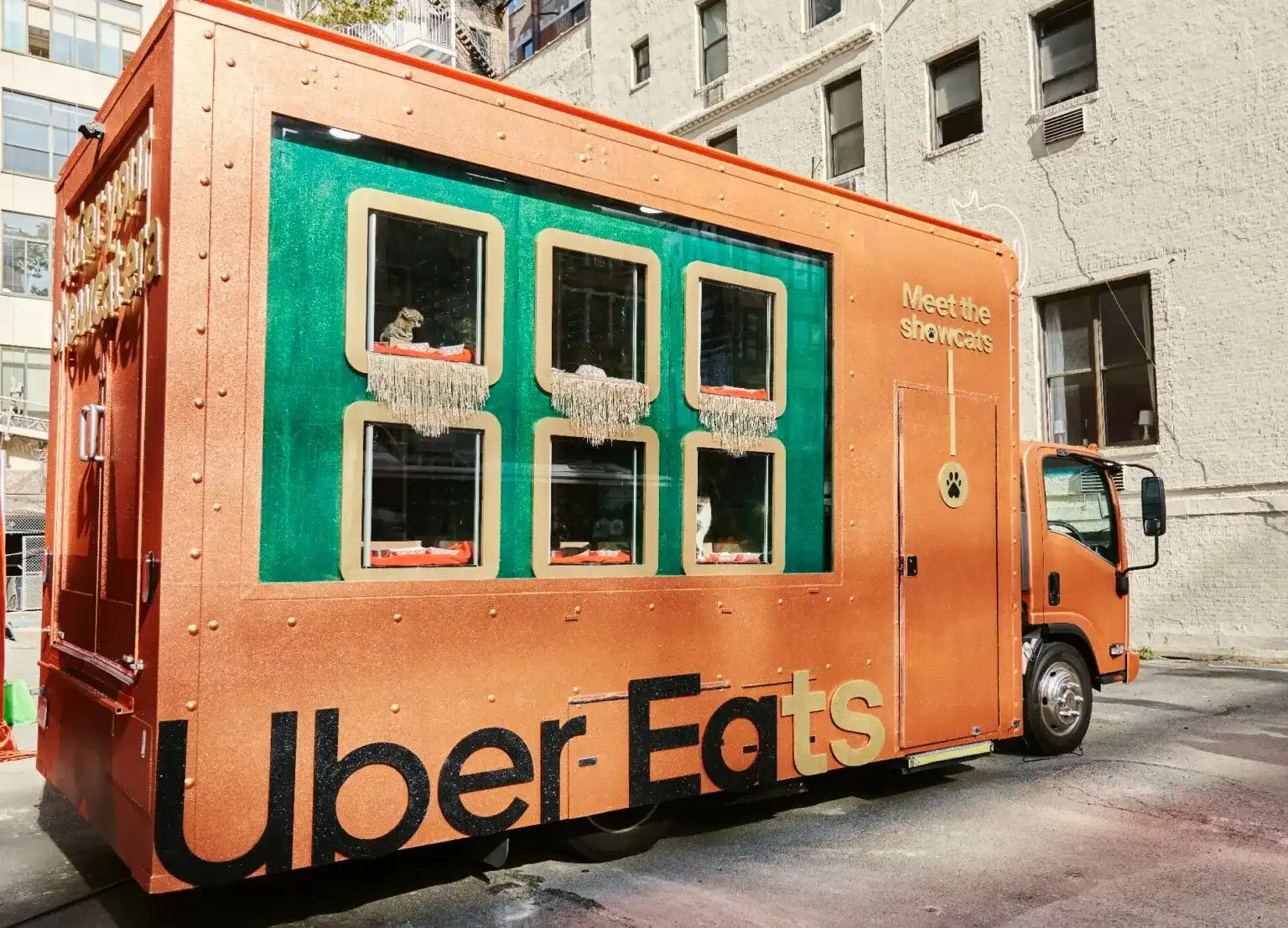 Caminhão de entrega Uber Eats laranja brilhante transformado com janelas que exibem gatos, promovendo "Showcats".