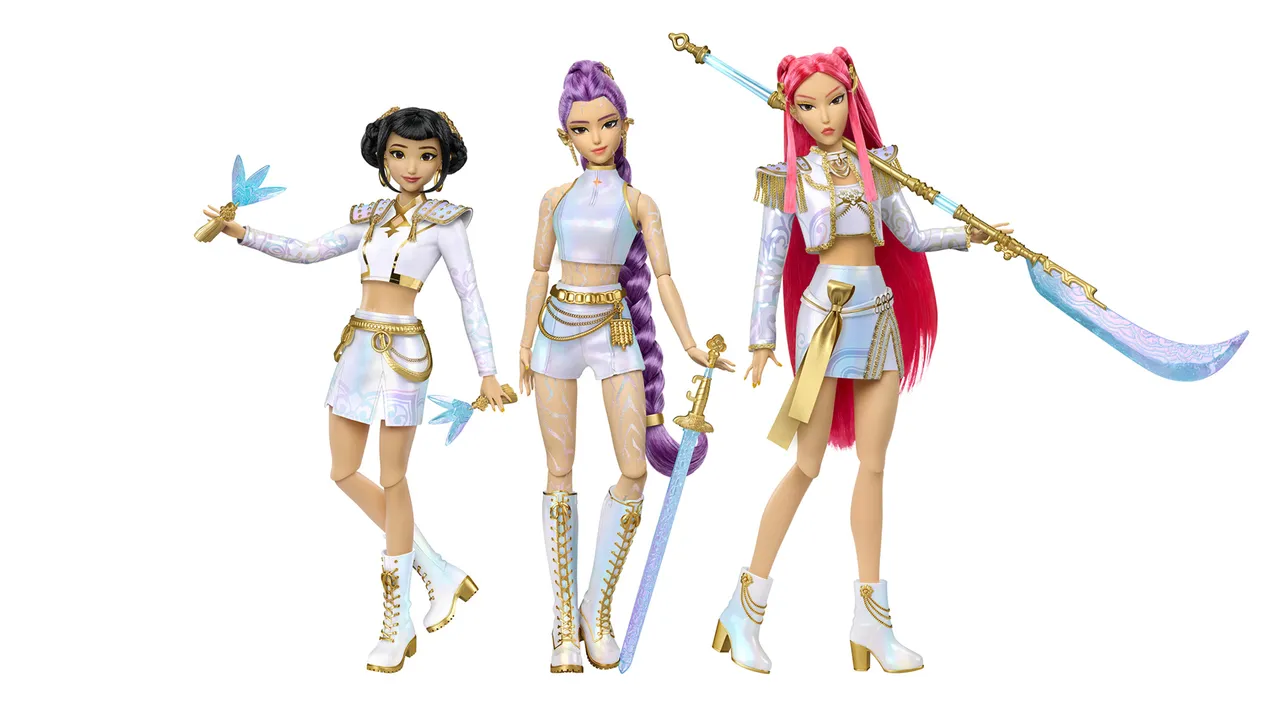 As três bonecas Mattel da coleção K-Pop Demon Hunters em um fundo branco. Elas usam roupas brancas e azuis com detalhes dourados e seguram armas estilizadas.