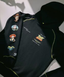Um moletom preto da colaboração Disney-Pixar Toy Story e Aston Martin F1. A manga apresenta estampas de Woody, Buzz Lightyear, Jessie e os Aliens. O corpo tem o logo Toy Story e o bordado "You've got a friend in me".