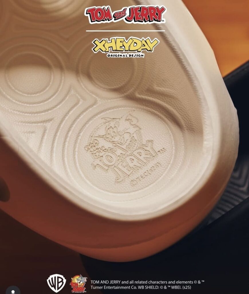Detalhe da palmilha de um chinelo XHeyDay Tom e Jerry bege, com o logotipo circular de Tom e Jerry em relevo.