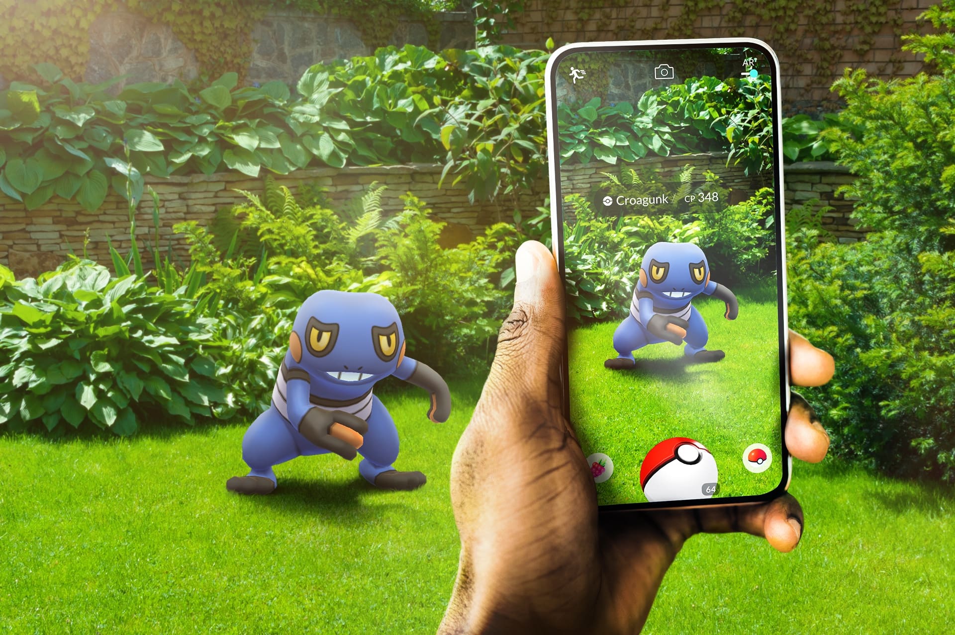 Uma mão segurando um celular exibindo o jogo Pokémon GO com um Croagunk de CP 348 na tela, que também aparece em realidade aumentada no gramado em frente.