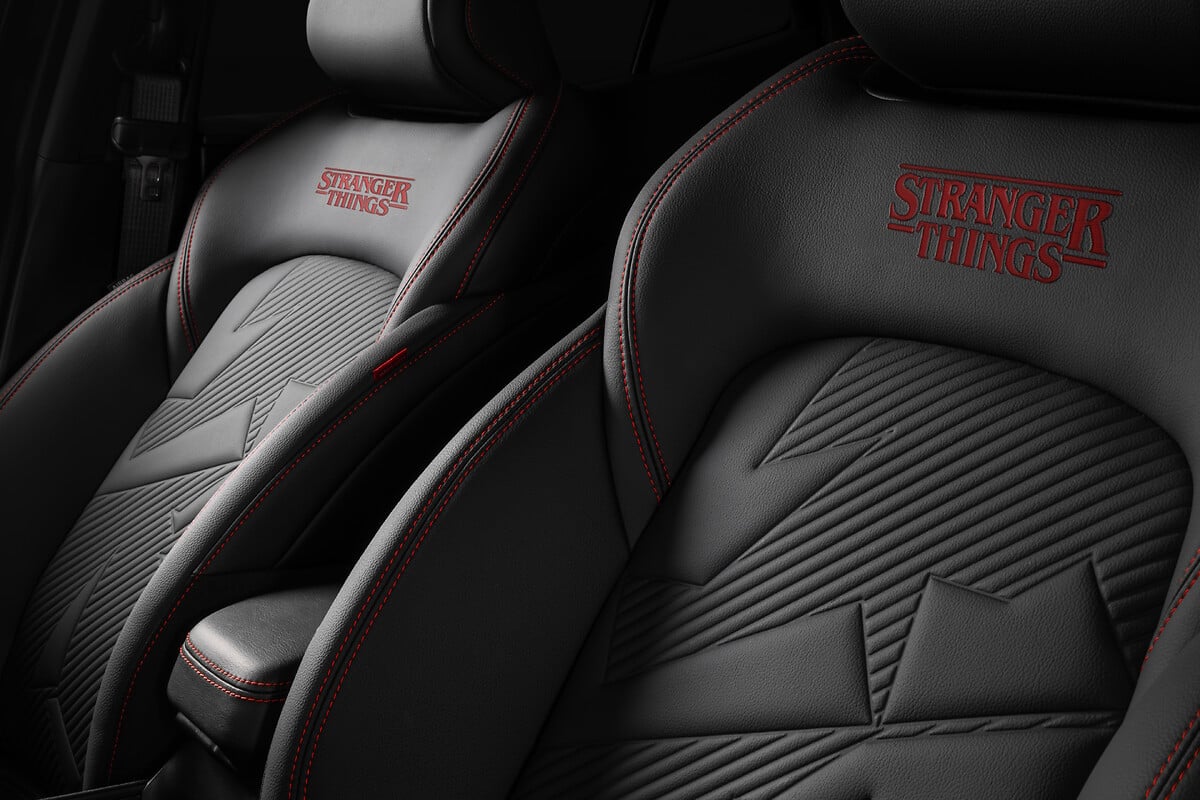 Detalhe do banco de carro preto com logo Stranger Things bordado em vermelho.
