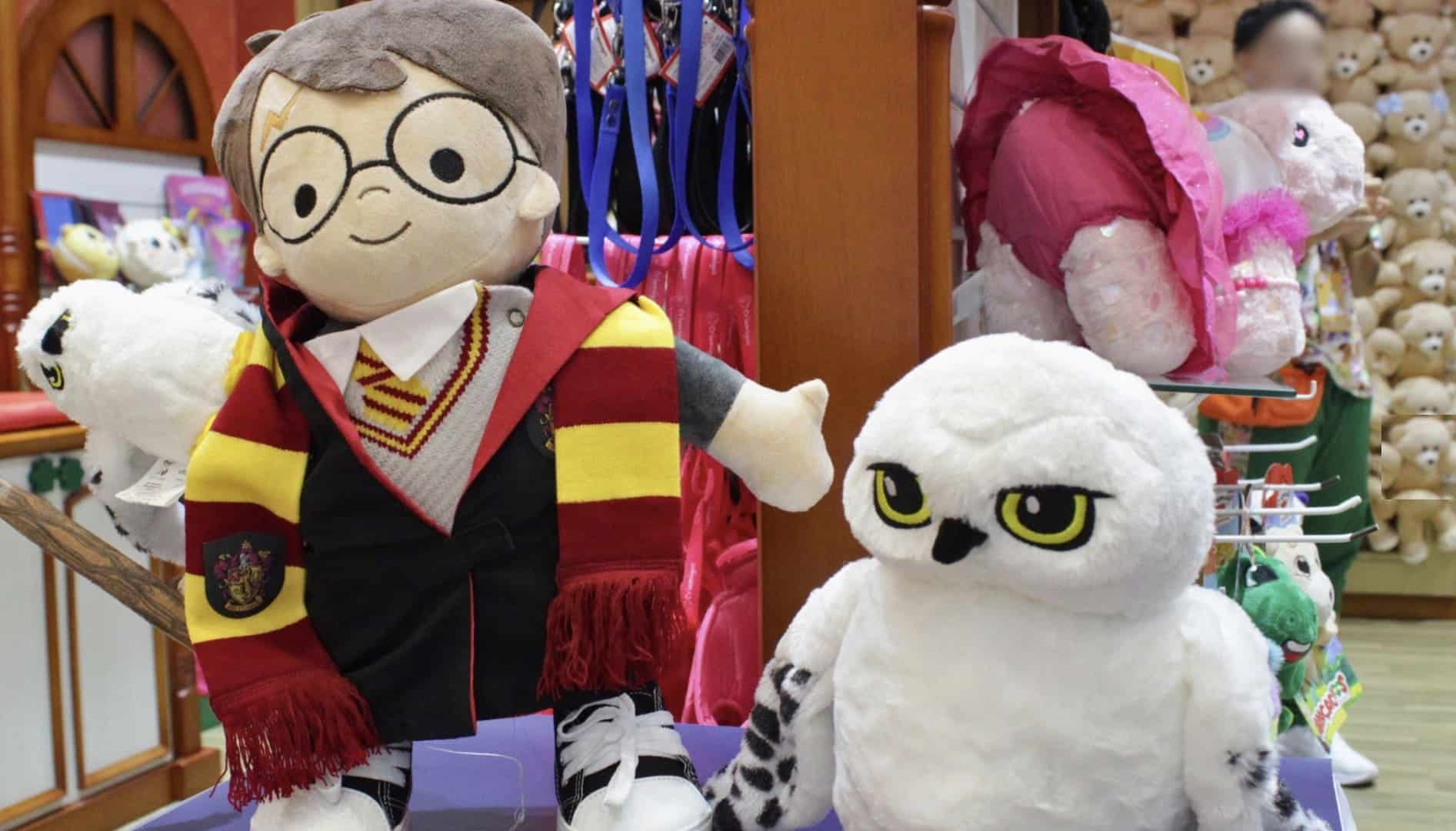 Boneco de pelúcia grande do Harry Potter em exposição ao lado de uma pelúcia da coruja Edwiges, dentro de uma loja.