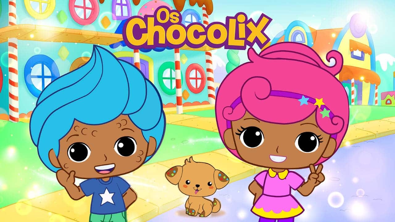 Dois personagens infantis com pele morena e olhos grandes, um de cabelo azul e outro de cabelo rosa, sorriem e acenam ao lado de um pequeno cachorro marrom. O cenário é uma rua colorida com casas que parecem feitas de doces. O título "Os Chocolix" está no topo.