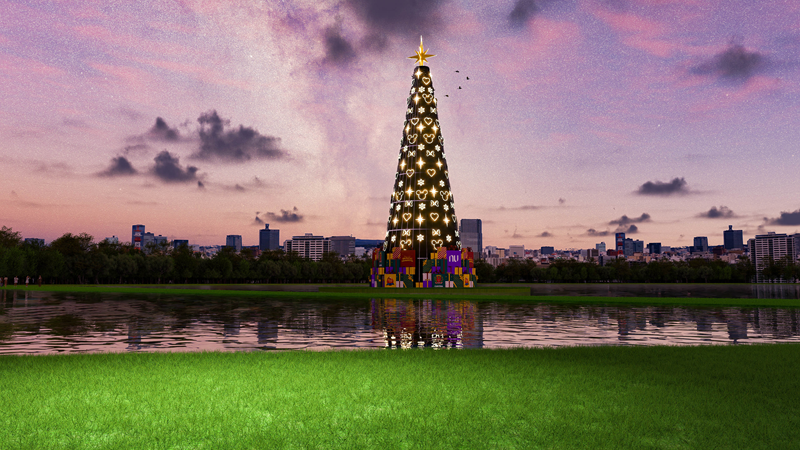Árvore de Natal gigante e iluminada, com desenhos de corações, na beira de um lago, com um skyline de cidade ao fundo, sob um céu estrelado.