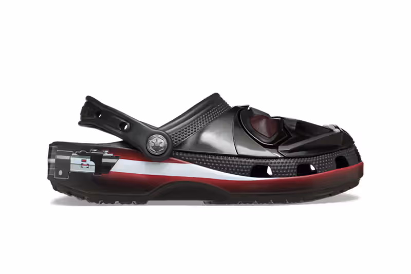 Visual lateral do Crocs preto de Darth Vader, mostrando a ponta em formato de capacete e a sola com um gráfico de sabre de luz vermelho e branco.