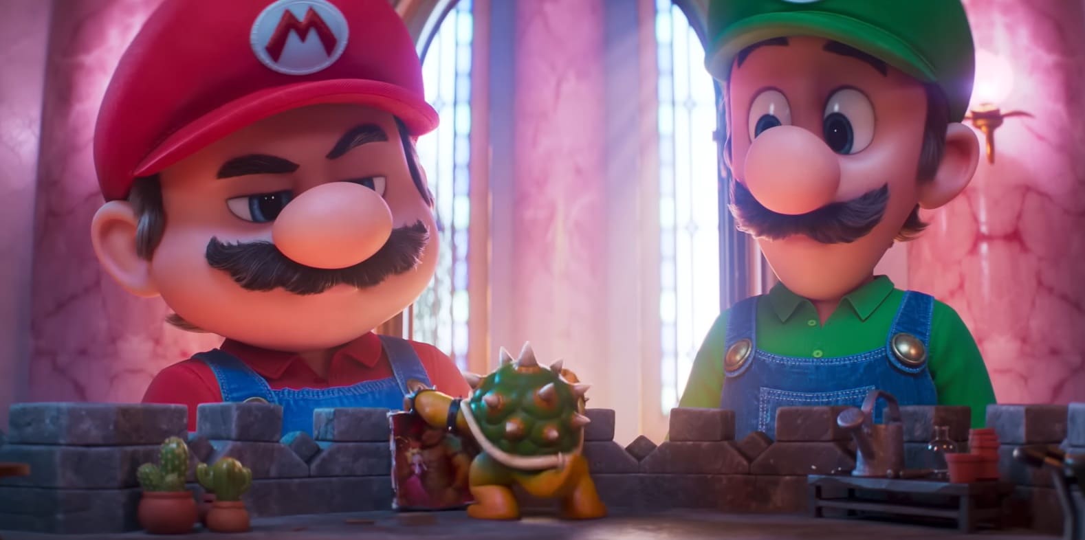 Close-up de Mario e Luigi olhando para uma pequena figura de Bowser em cima de um muro de tijolos.
